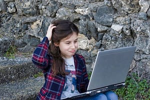Puzzled 11+ girl with laptop